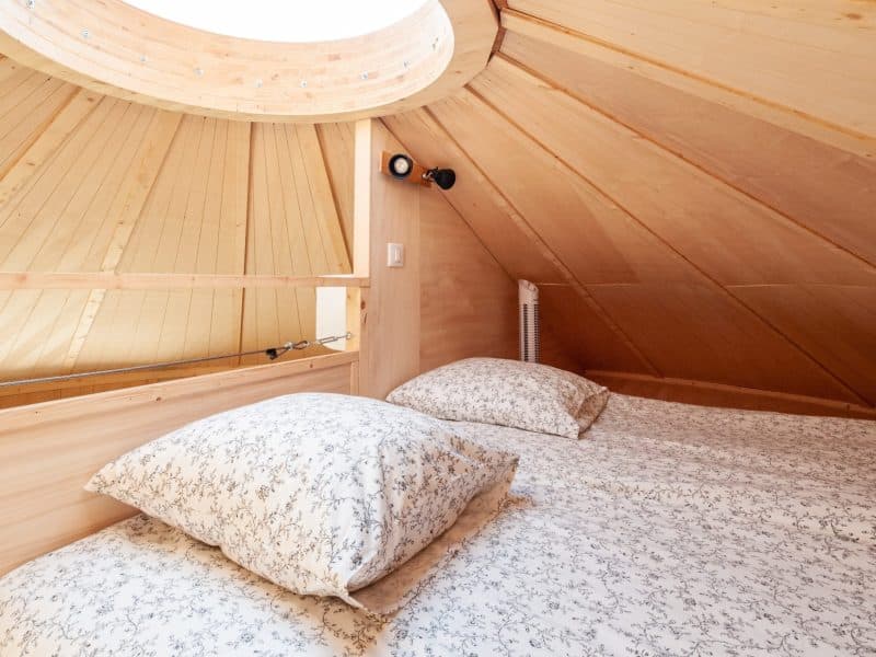 Chalet en bois avec un plafond en pente et des lits douillets à la literie fleurie.