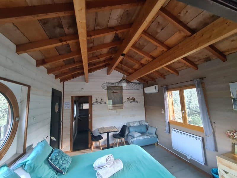 Chalet cosy avec plafond en bois, lit confortable et vue sur la nature.