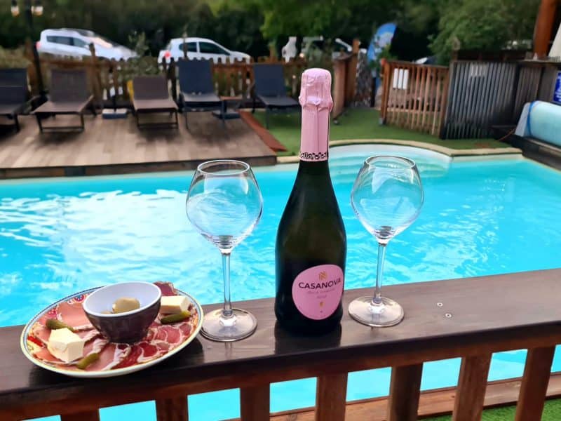 Chalet avec piscine, flûtes de champagne et assiette de charcuterie au bord de leau.
