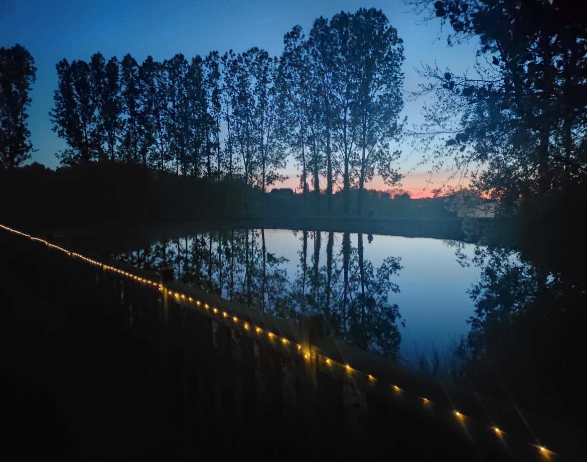 Hébergement insolite en Limousin, cabane au bord dun lac, éclairage féerique au crépuscule.