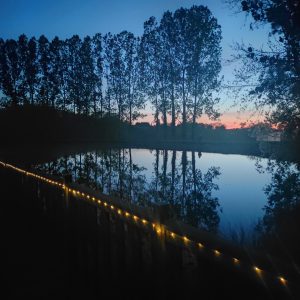 Hébergement insolite en Limousin, cabane au bord dun lac, éclairage féerique au crépuscule.