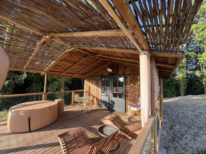Chalet en bois avec terrasse, jacuzzi et mobilier en bois naturel.