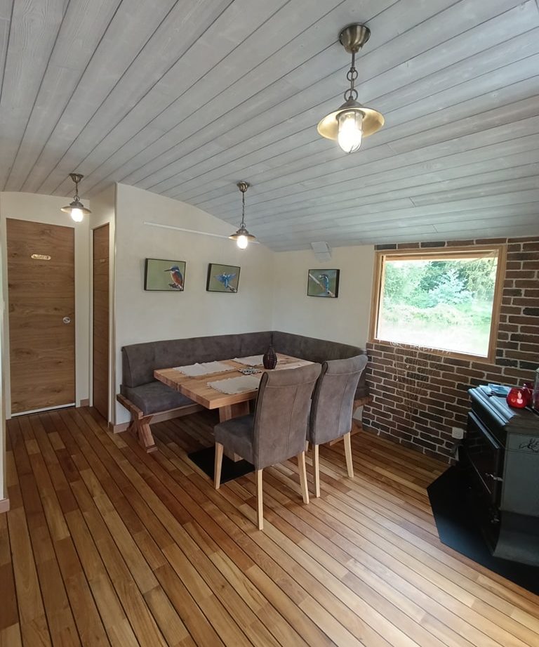 Hébergement insolite à Limousin : intérieur chaleureux avec parquet en bois et coin repas.