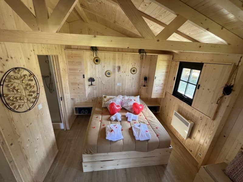 Chalet en bois chaleureux avec lit décoré de cœurs et de pétales de fleurs.