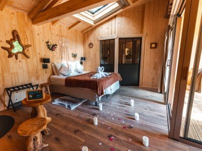 Chalet en bois chaleureux avec lit douillet et pétales de fleurs au sol.
