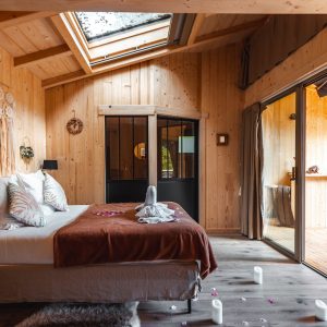 Chalet en bois chaleureux avec lit douillet et baie vitrée sur la nature.