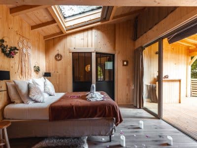 Chalet en bois chaleureux avec lit douillet et baie vitrée sur la nature.