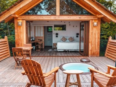 Cabane en bois avec terrasse, vue sur la nature, ambiance chaleureuse et cosy.