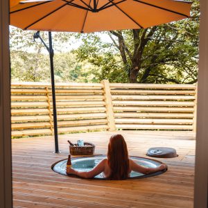 Hébergement insolite en Hauts-de-France : jacuzzi sur terrasse en bois, ambiance relaxante.