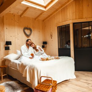 Cabane en bois dans les Hauts-de-France, avec un lit douillet et lumière naturelle.