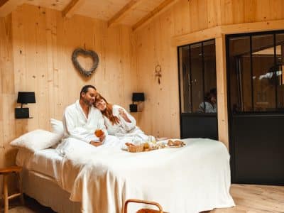 Cabane en bois dans les Hauts-de-France, avec un lit douillet et lumière naturelle.