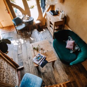 Hébergement insolite en Bretagne : intérieur chaleureux avec un canapé vert et bois naturel.