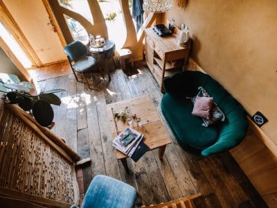 Hébergement insolite en Bretagne : intérieur chaleureux avec un canapé vert et bois naturel.