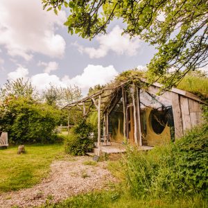 Cabane en bois atypique en Bretagne, entourée de verdure et de chaises longues.