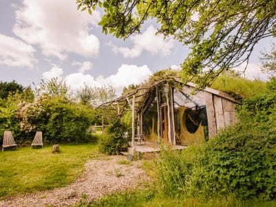 Cabane en bois atypique en Bretagne, entourée de verdure et de chaises longues.