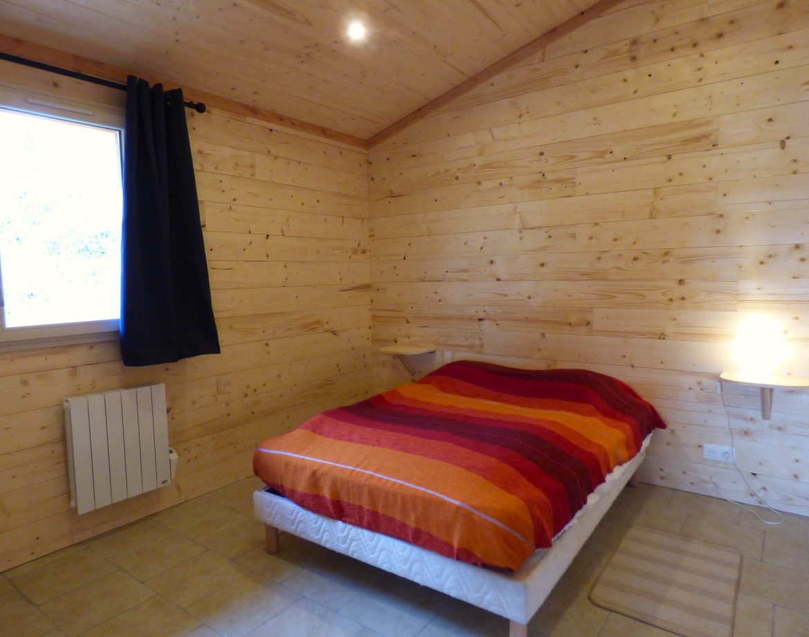 Chalet en bois chaleureux en Auvergne, avec lit douillet et décoration colorée.
