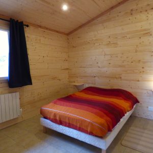 Chalet en bois chaleureux en Auvergne, avec lit douillet et décoration colorée.