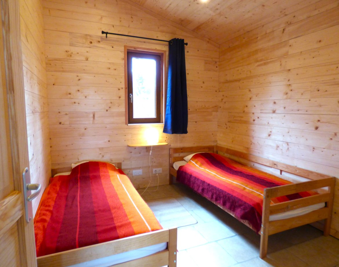 Chalet en bois à Auvergne, avec lits simples et ambiance chaleureuse.