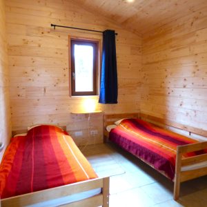 Chalet en bois à Auvergne, avec lits simples et ambiance chaleureuse.