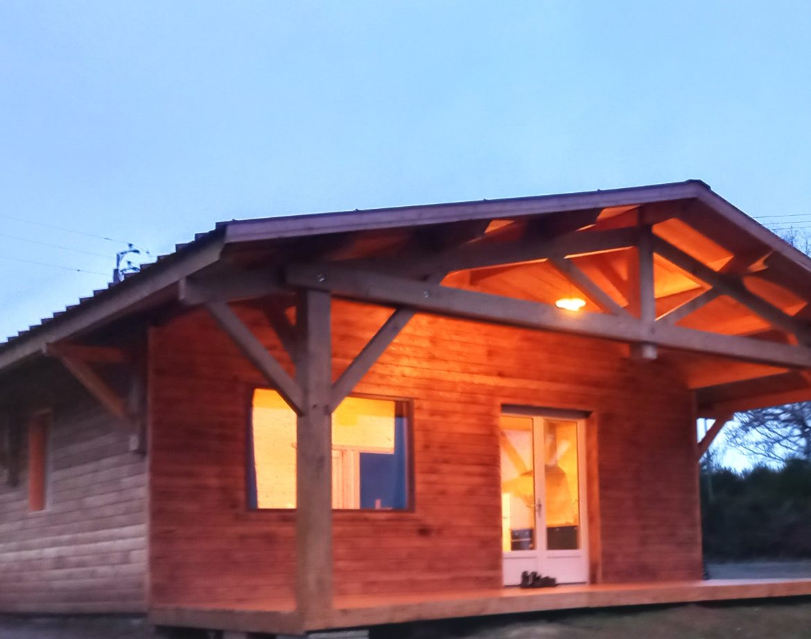 Cabane en bois chaleureuse à Auvergne, éclairée par des lumières douces au crépuscule.