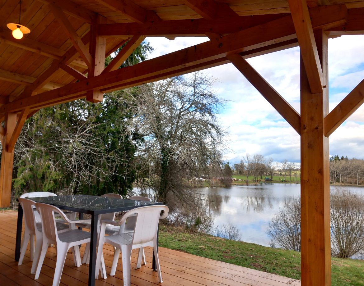 Hébergement insolite en Auvergne avec terrasse en bois surplombant un lac paisible.