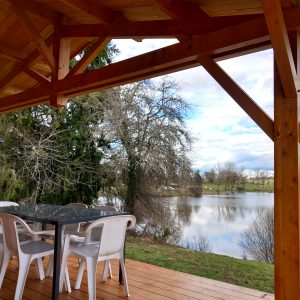 Hébergement insolite en Auvergne avec terrasse en bois surplombant un lac paisible.