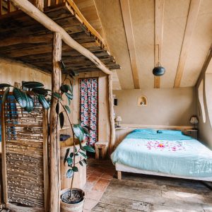 Hébergement insolite en Bretagne : chambre chaleureuse avec lit douillet et décoration bois.