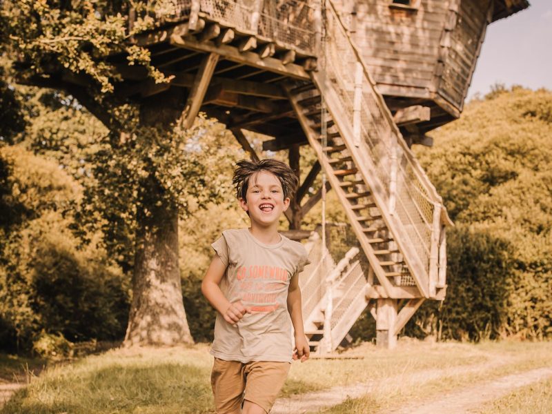 Cabane dans les arbres en Pays de la Loire, enfant joyeux courant sur le chemin.