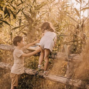 Enfants jouant près dune cabane dans les arbres, entourés de verdure dorée.