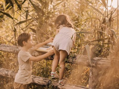 Enfants jouant près dune cabane dans les arbres, entourés de verdure dorée.