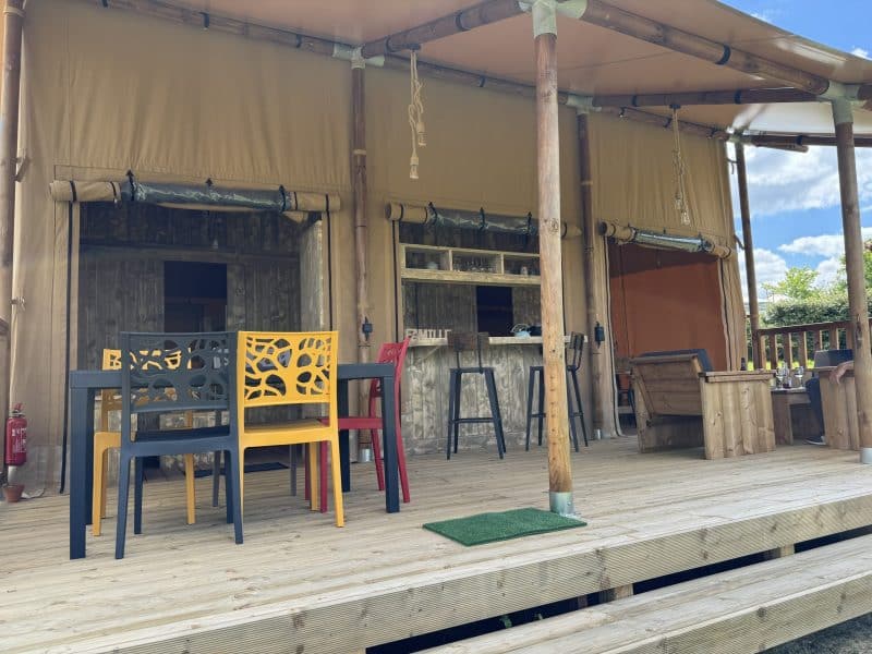 Tente safari avec terrasse en bois et chaises colorées, idéale pour un séjour nature.