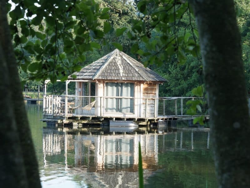 Cabane sur pilotis au bord dun lac, entourée de verdure paisible.