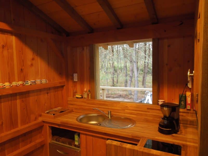 Cabane en bois avec cuisine équipée et vue sur la forêt.
