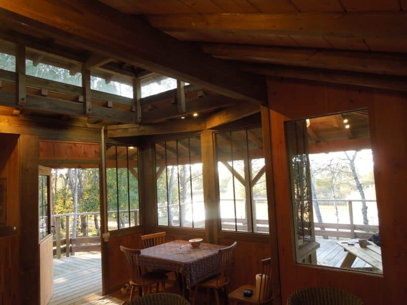 Cabane en bois avec grandes fenêtres, vue sur la nature environnante.