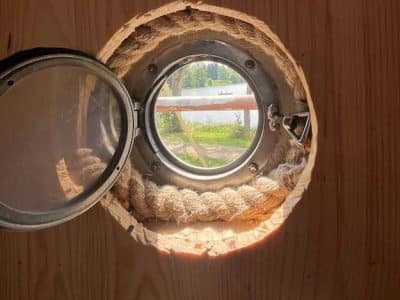 Hébergement insolite en Auvergne : hublot rond offrant une vue sur le lac.