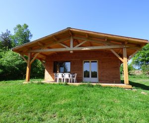 Chalet en bois à Auvergne, avec terrasse et vue sur la nature verdoyante.