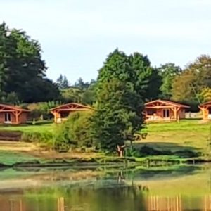 Chalets en bois au bord dun lac, entourés de verdure en Auvergne.
