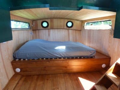 Hébergement insolite en Auvergne : cabane avec lit en bois et fenêtres rondes.