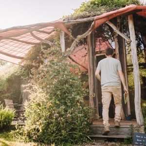 Cabane en bois en Bretagne, entourée de verdure et dune toile colorée.