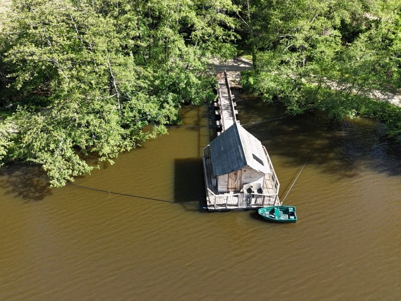 Cabane flottante au bord de leau, entourée de verdure luxuriante en Auvergne-Rhône-Alpes.