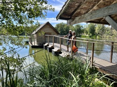 Hébergement insolite en cabane sur leau, ponton en bois entouré de verdure.