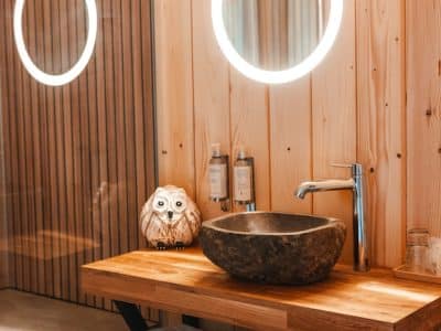 Salle de bain moderne dans un hébergement insolite en bois, avec lavabo en pierre.