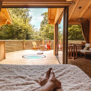 Chalet en bois avec jacuzzi privé et vue sur la nature verdoyante.