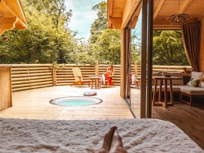 Chalet en bois avec jacuzzi privé et vue sur la nature verdoyante.