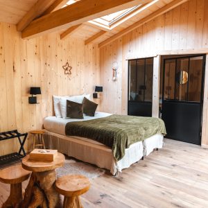 Chalet en bois chaleureux avec lit douillet et décor naturel dans les Hauts-de-France.