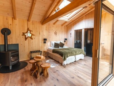 Cabane en bois chaleureuse avec un lit douillet et un poêle à bois.