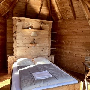 Cabane en bois chaleureuse avec lit douillet et décoration naturelle.