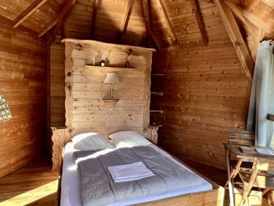 Cabane en bois chaleureuse avec lit douillet et décoration naturelle.