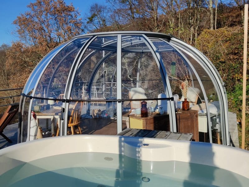 Dôme transparent avec jacuzzi, offrant une vue panoramique sur la nature environnante.