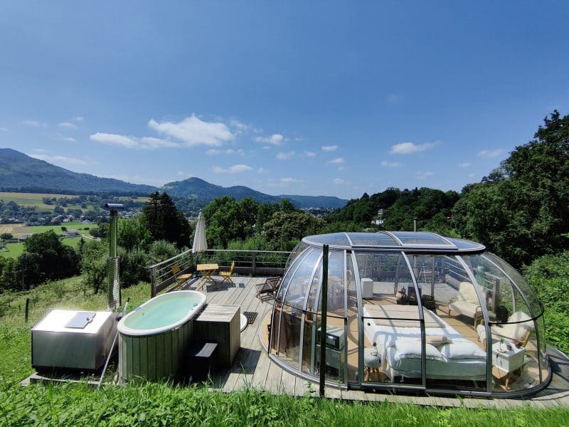 Hébergement insolite en bulle avec jacuzzi, vue panoramique sur la vallée verdoyante.